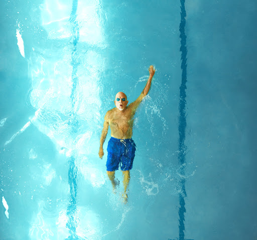 A swimmer diving through the clear blue water of a pool.