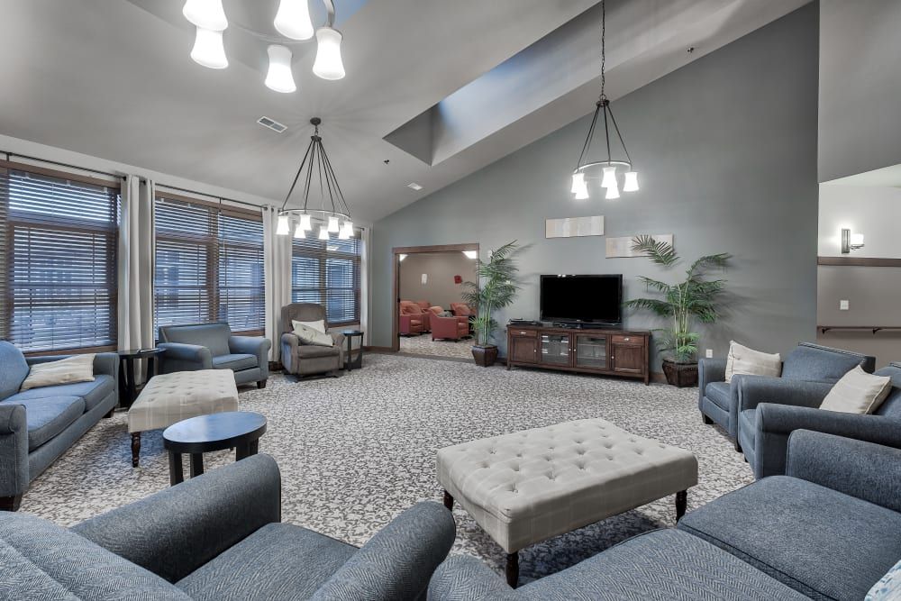 A spacious and modern living room with comfortable seating, elegant chandeliers, and a television.