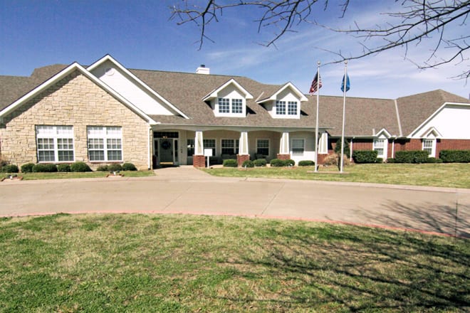 A residential building with a well-maintained lawn and flags at the entrance.