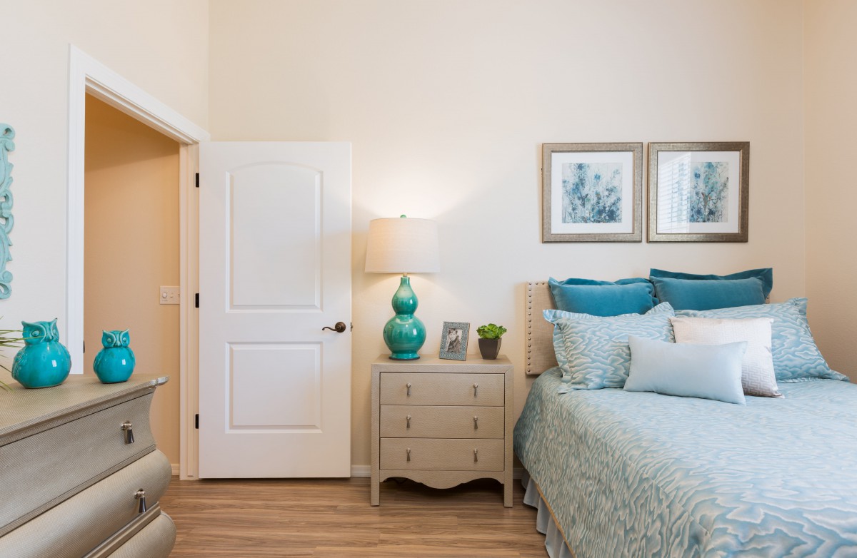 A cozy bedroom with a neatly arranged bed, nightstand, and tasteful decor.