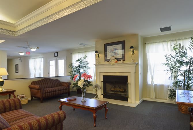 A cozy living room featuring a fireplace, sofas, and a wooden coffee table adorned with flowers.