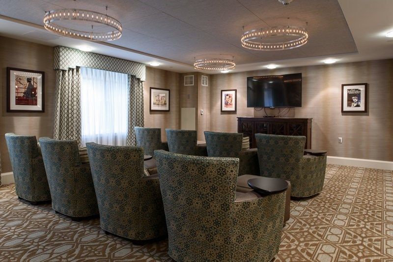 A cozy conference room setup with upholstered chairs and a large TV for presentations.
