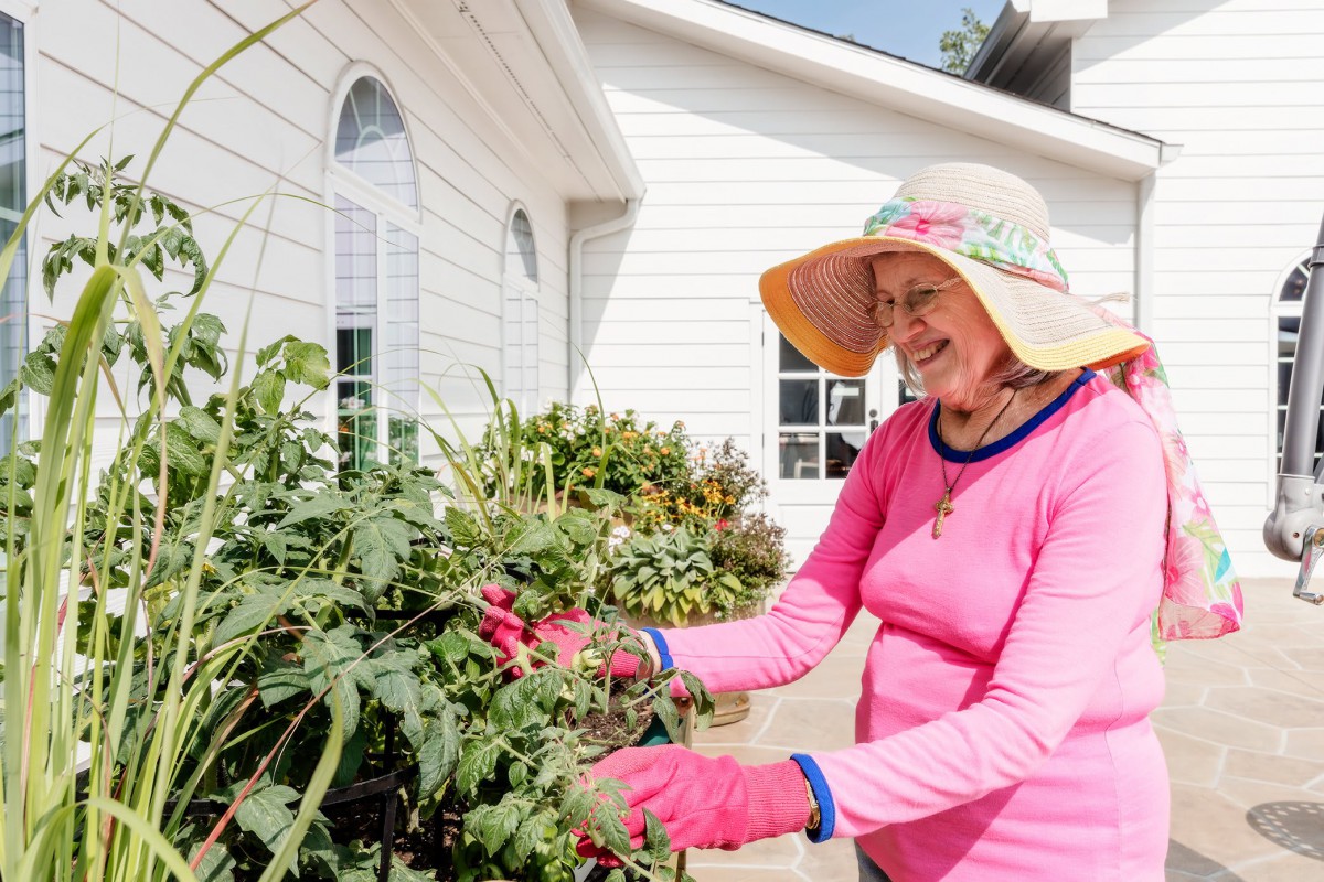 A woman enjoying a sunny day gardening outside her home.