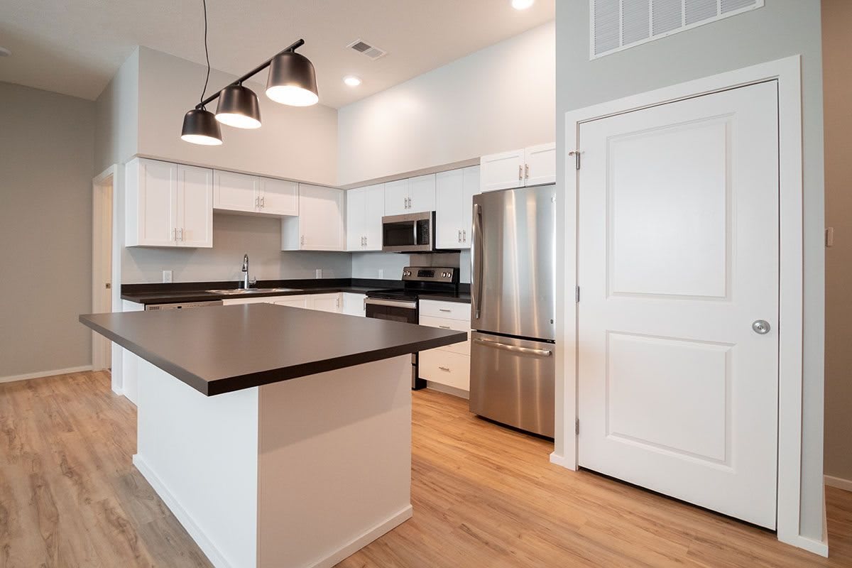 A modern kitchen featuring a central island, stainless steel appliances, and minimalist lighting.