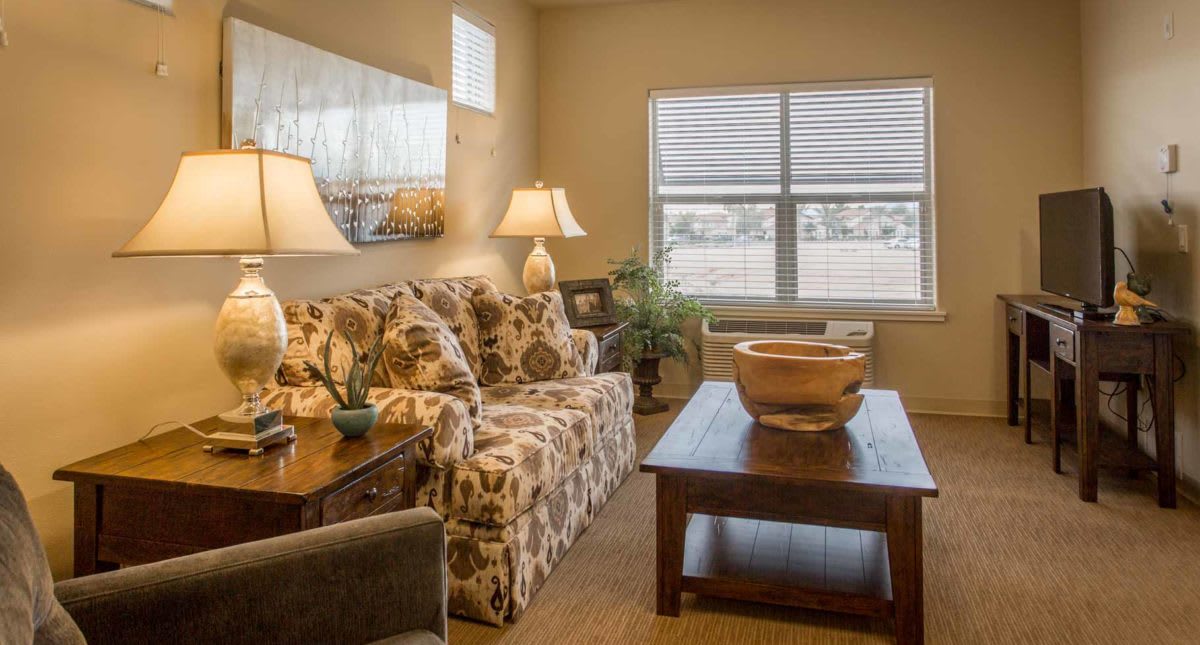 A cozy living room with a patterned sofa, wooden coffee table, and warm lighting from lamps.