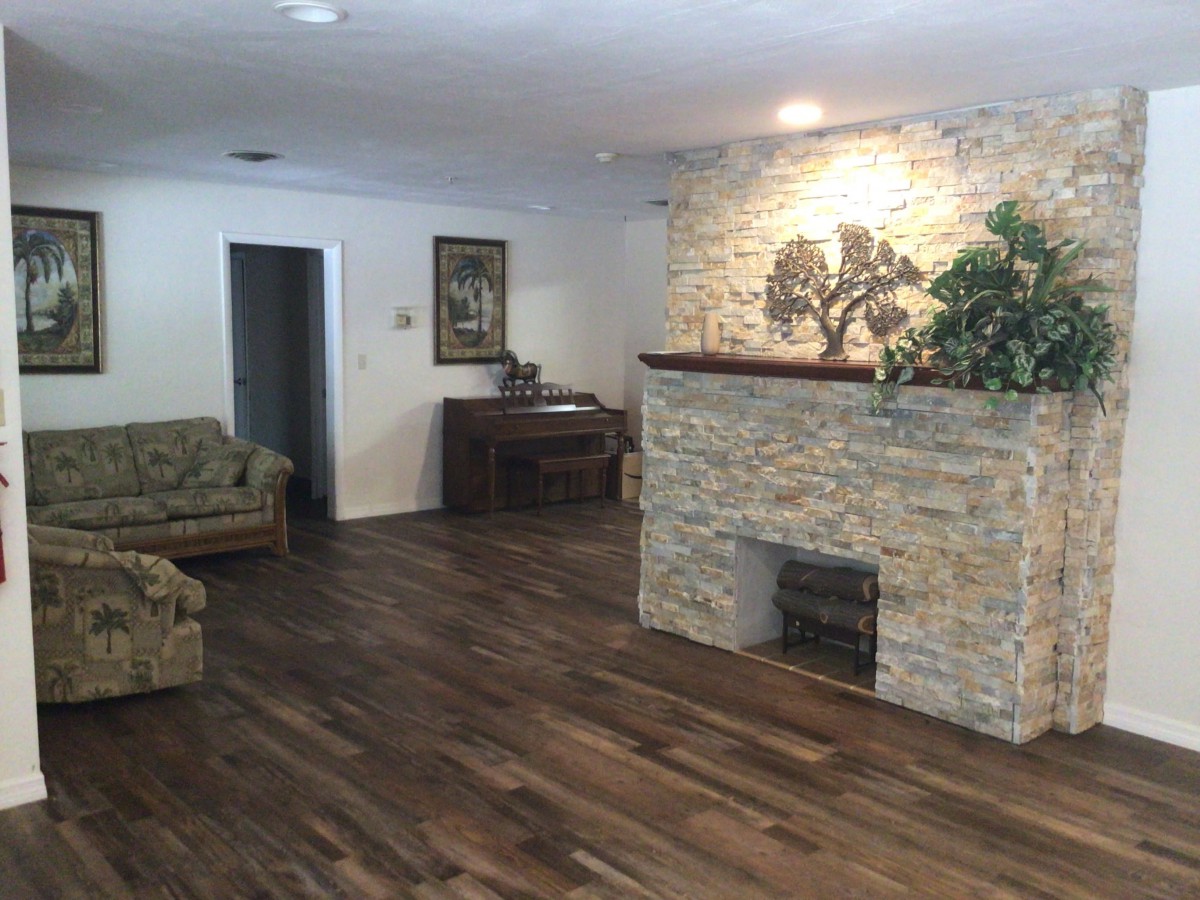 A cozy living room with a stone fireplace and hardwood floors.