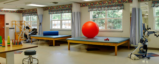 A spacious therapy room featuring a bright red exercise ball and two treatment tables.