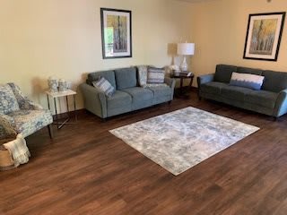 A cozy living room with comfortable seating, artwork on the wall, and a soft rug on a wooden floor.
