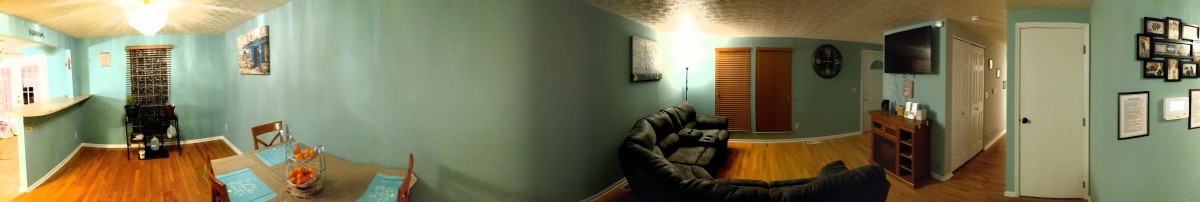 A cozy living room with a couch, painting, and floor lamp against a green wall.