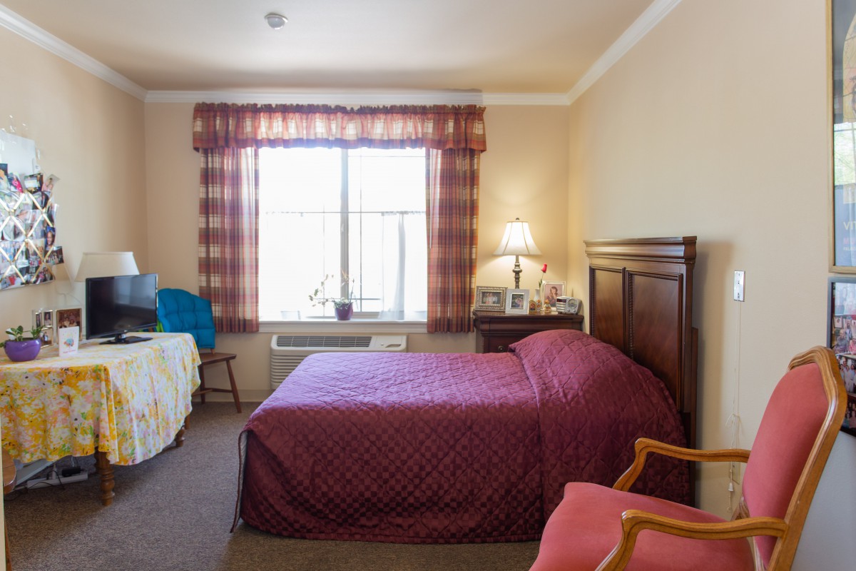A well-lit hotel bedroom with two beds and a window.