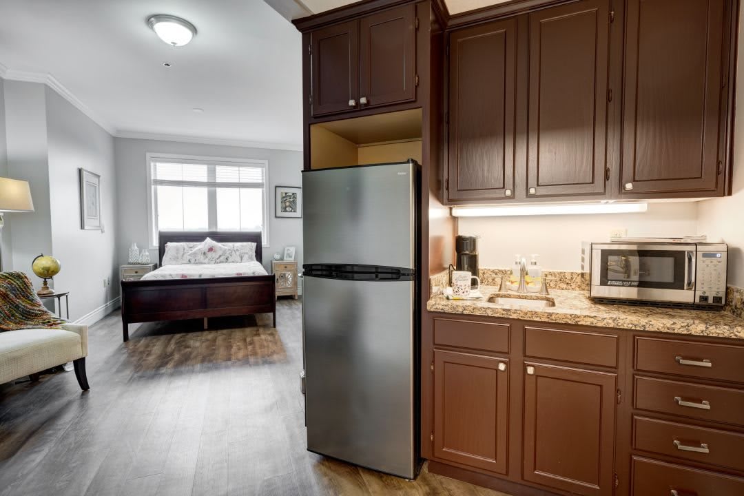 A modern studio apartment featuring a compact kitchen with stainless steel appliances and a cozy bedroom area.