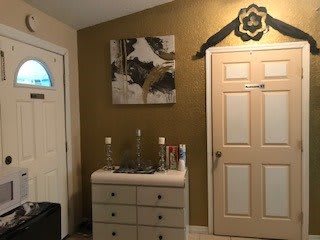 A well-decorated entryway featuring a dresser, artwork on the wall, and a closed door.