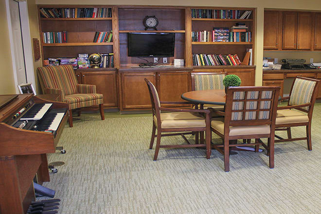A cozy library room with bookshelves, a table, and chairs.