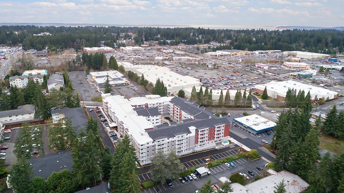 Aerial view of a residential complex surrounded by trees and parking areas.