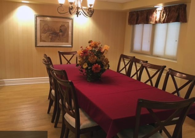 A cozy dining room with a red tablecloth and floral centerpiece.