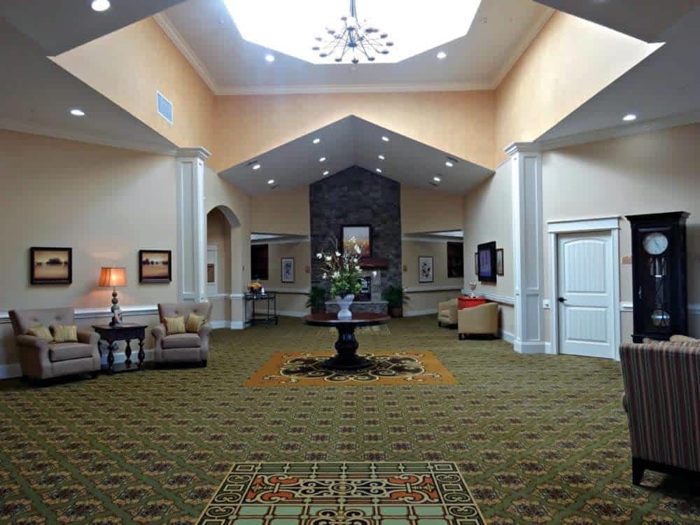 A spacious lobby with elegant decor, featuring a central table and chandelier.