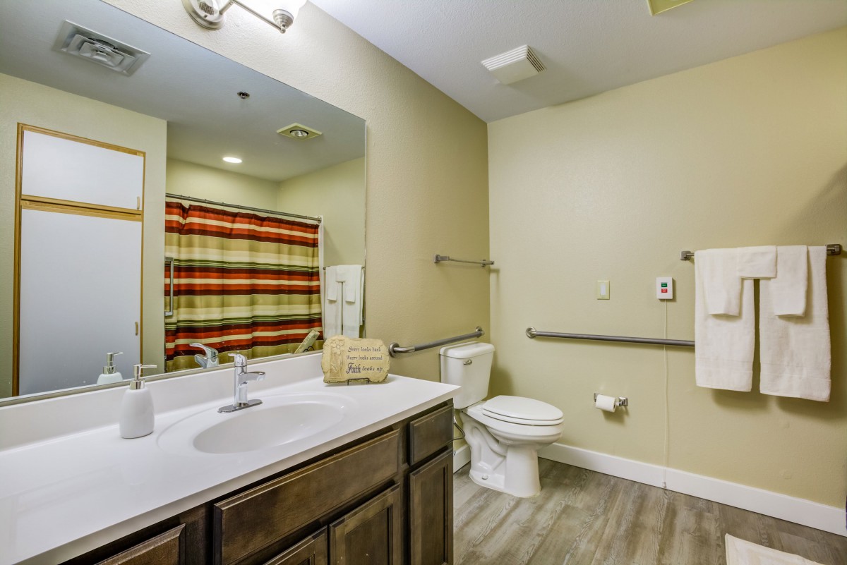 A modern bathroom featuring a sink, toilet, and shower with a colorful curtain.
