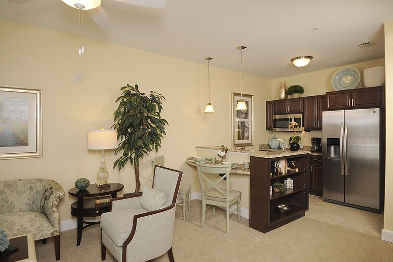 A cozy open-plan living space with a small kitchen and dining area, featuring modern furniture and elegant lighting.