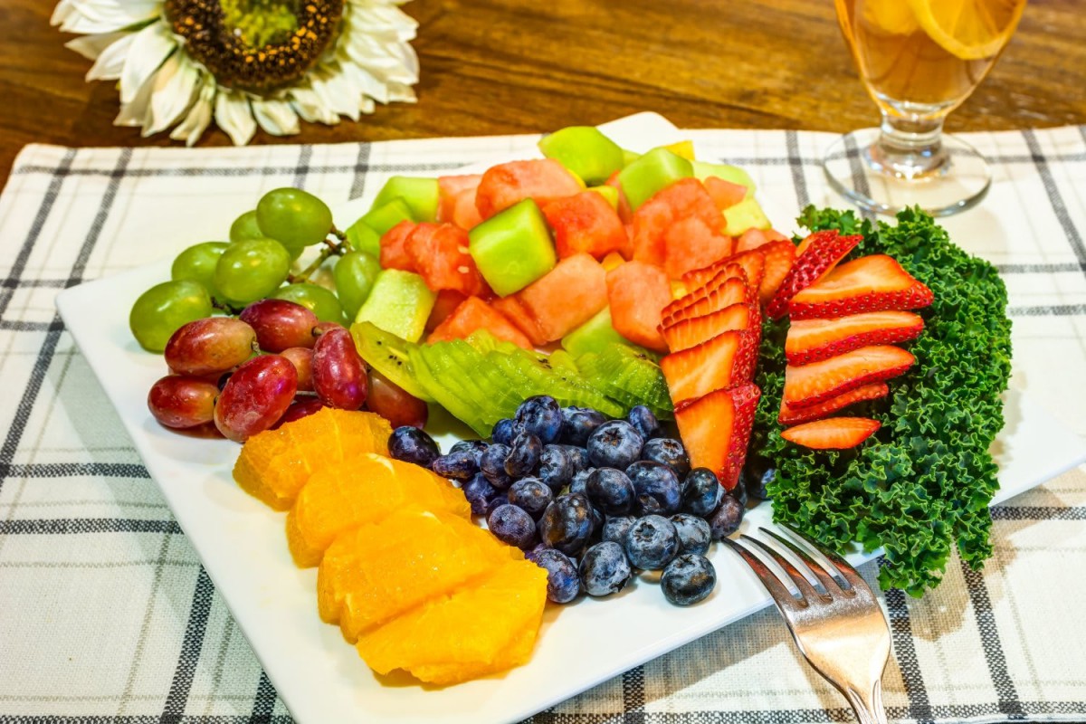 A colorful fruit platter featuring an assortment of grapes, watermelon, honeydew melon, strawberries, mango slices, and blueberries.
