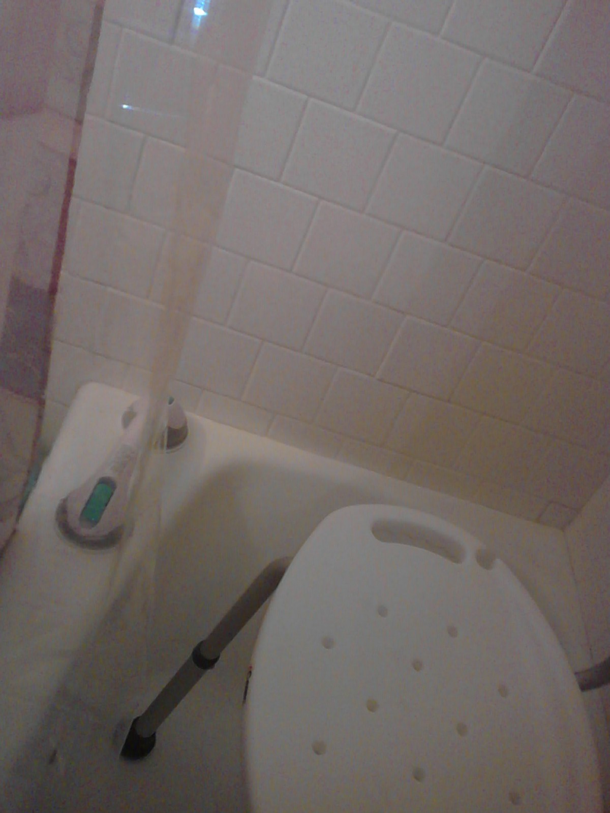 A bathroom with a bathtub, shower curtain, and toilet.