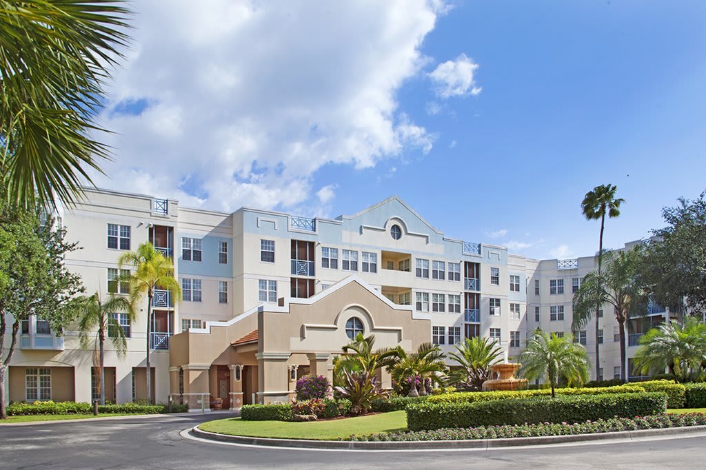 A large residential building with palm trees under a clear blue sky.
