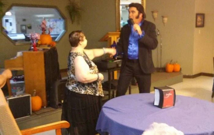 A performer sings to an audience member at an indoor event.