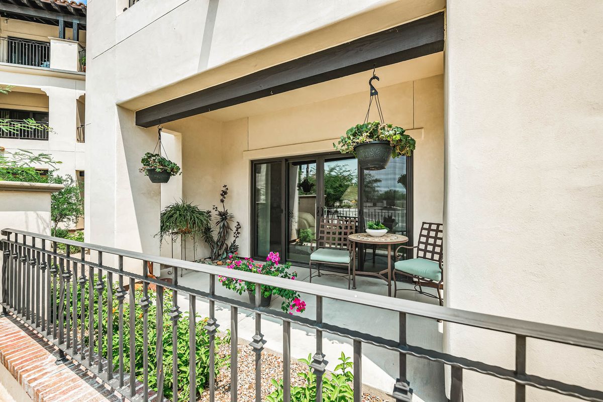 A cozy apartment balcony featuring hanging plants and comfortable outdoor seating.