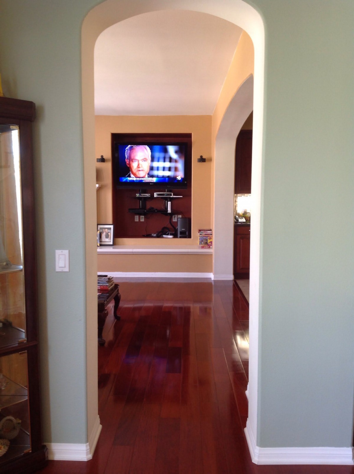 A view into a living room with a television mounted on the wall and a wooden floor.