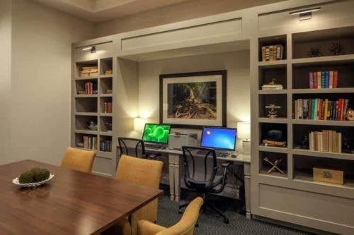 A well-organized office space with computers, bookshelves, and a conference table.