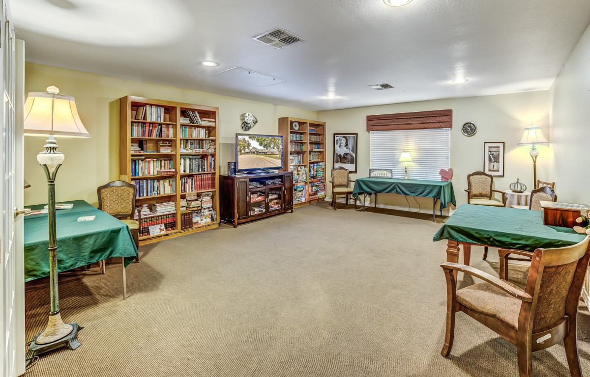 A cozy library room with bookshelves, tables, and chairs for reading.