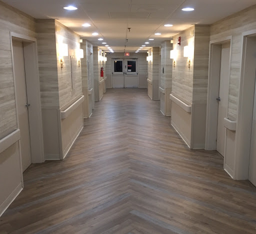 A view of a well-lit interior hallway with multiple doors and a wooden floor design.