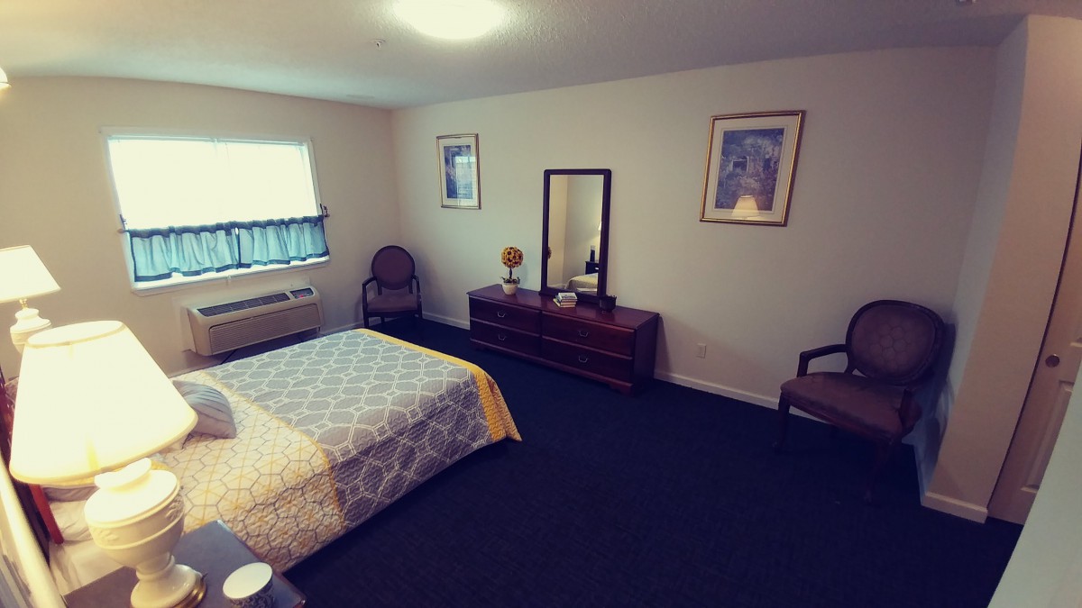 A neatly arranged bedroom with a bed, dresser, and mirror.