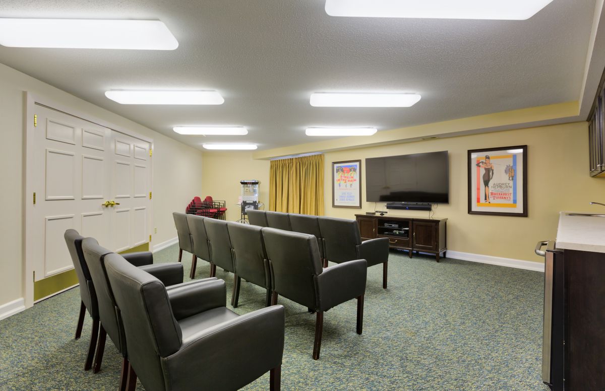 A spacious home theater room with arranged seating and a large television screen.