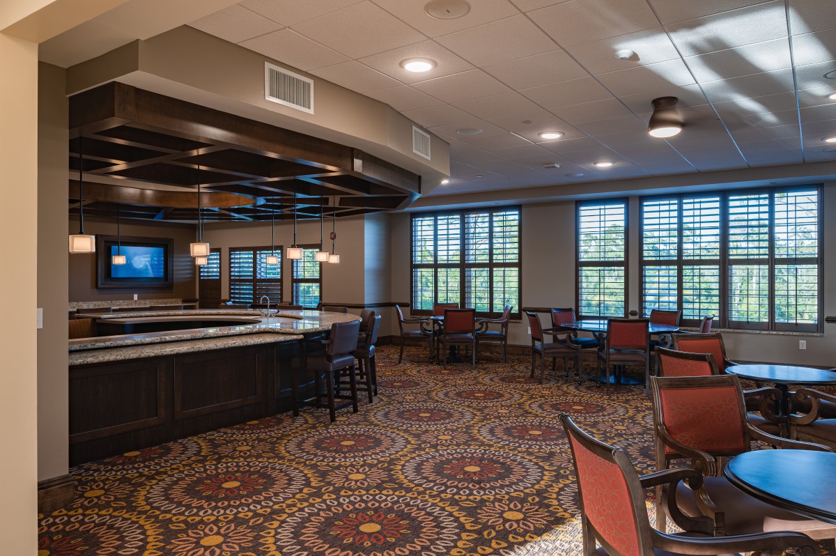 A restaurant interior featuring a bar area with seating and decorative carpeting.