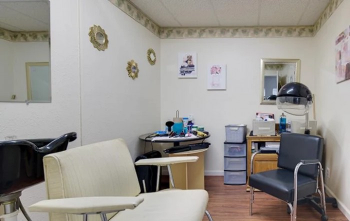 A cozy hair salon interior with chairs, beauty products, and wall decorations.