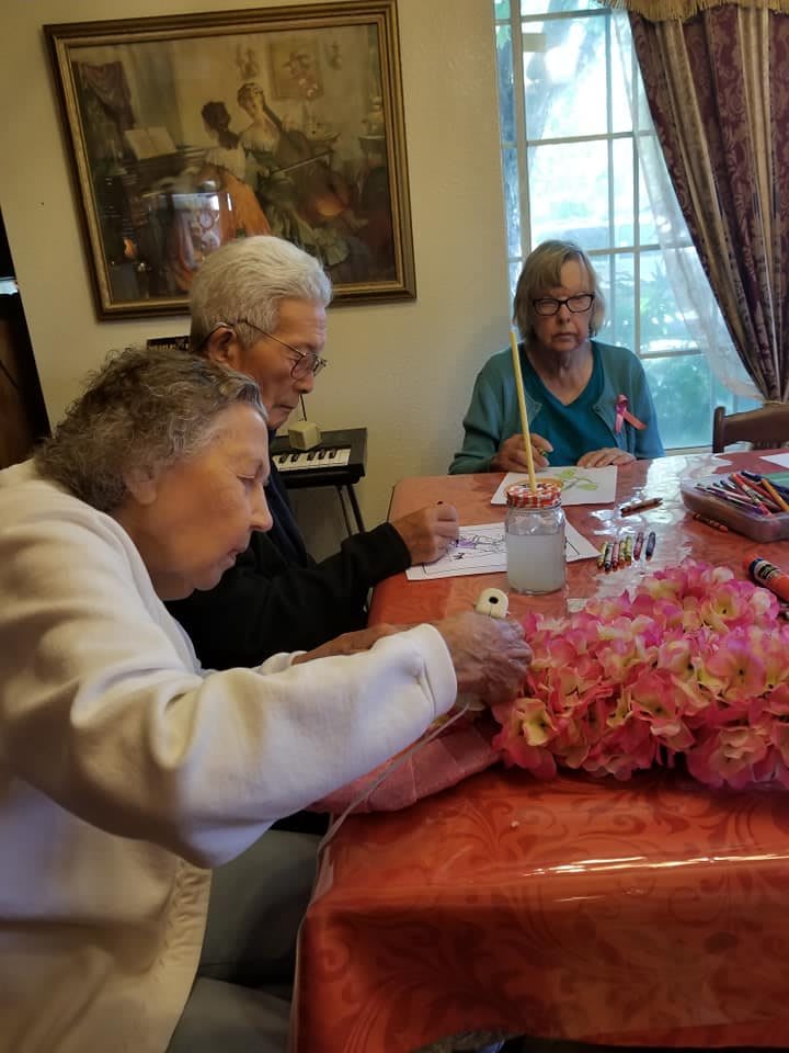 A group of seniors engaged in a crafting and painting activity together indoors.