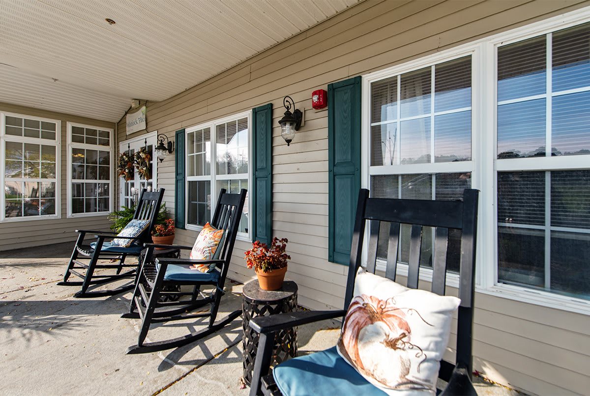 A cozy porch featuring rocking chairs and decorative elements like pillows and potted plants.