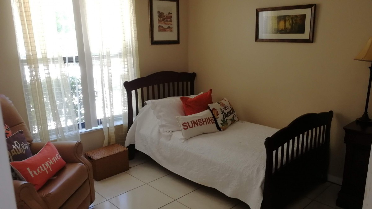 A cozy bedroom with a twin bed, neatly arranged pillows, and decorative artwork on the walls.