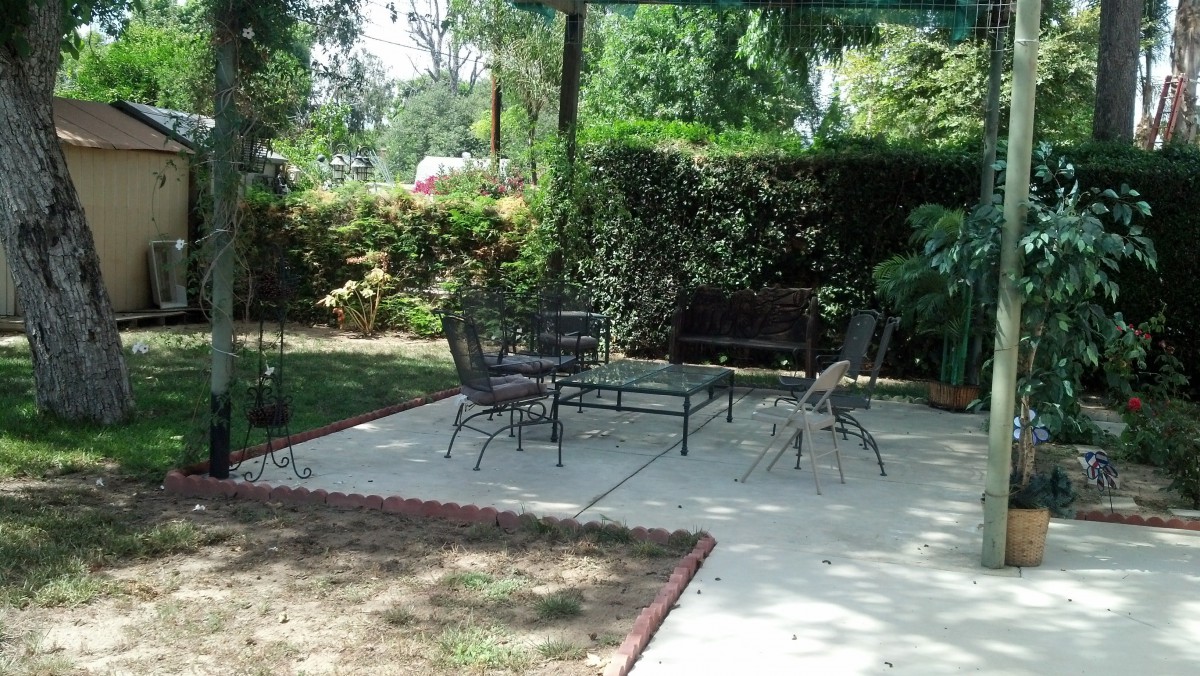 A peaceful garden patio with outdoor furniture and lush greenery.