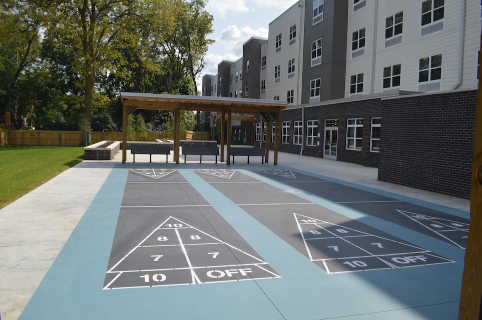 An outdoor shuffleboard court next to an apartment building on a sunny day.