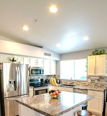 A modern kitchen featuring stainless steel appliances, granite countertops, and bright lighting.