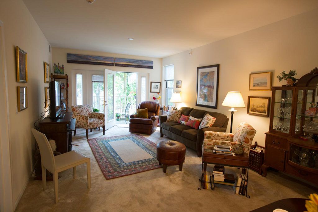 A cozy living room with comfortable seating, artwork on the walls, and a large carpet.