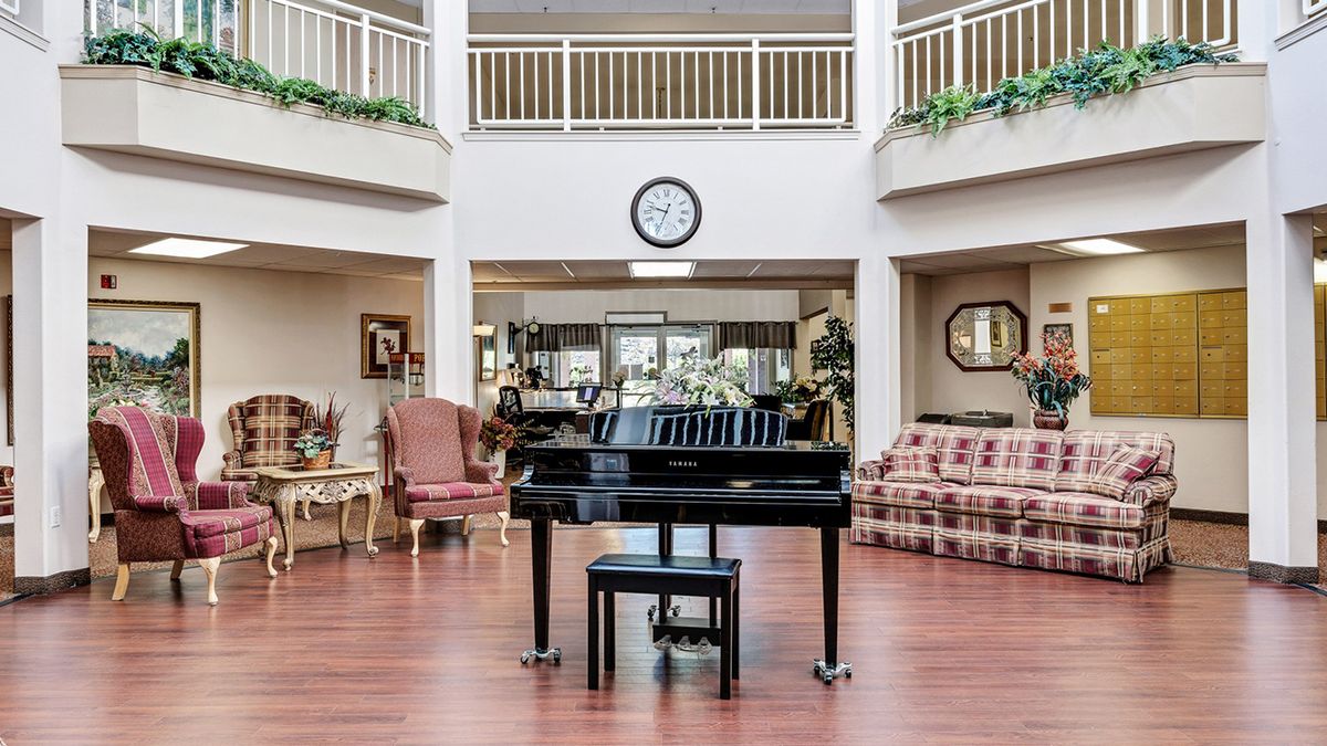 A spacious lobby featuring a grand piano, surrounded by comfortable seating and a clock on the wall.