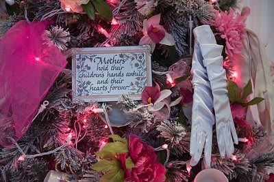 A decorative arrangement featuring a heartfelt message for mothers surrounded by pink flowers and lights.