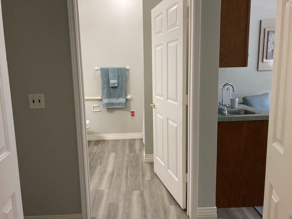 A view through an open doorway showing a bathroom with a sink and modern flooring.