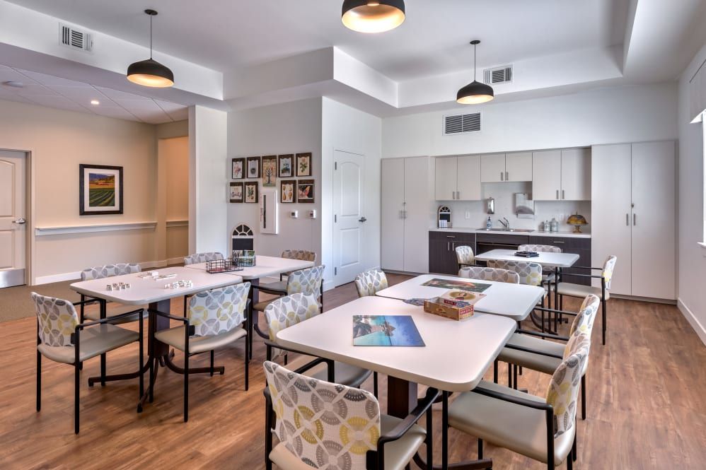 A modern meeting space with tables, chairs, and a kitchen area.