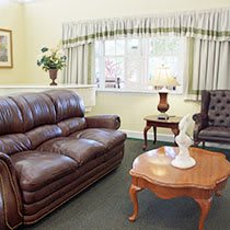 A cozy living room with a leather sofa, an armchair, and a wooden coffee table.