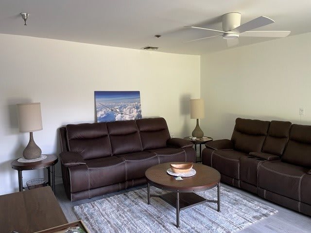 A cozy living room with leather sofas, a coffee table, and modern decor.