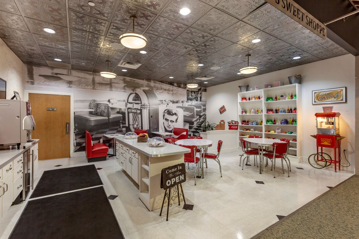A retro-style diner with vintage decor, featuring red chairs and a large mural on the wall.