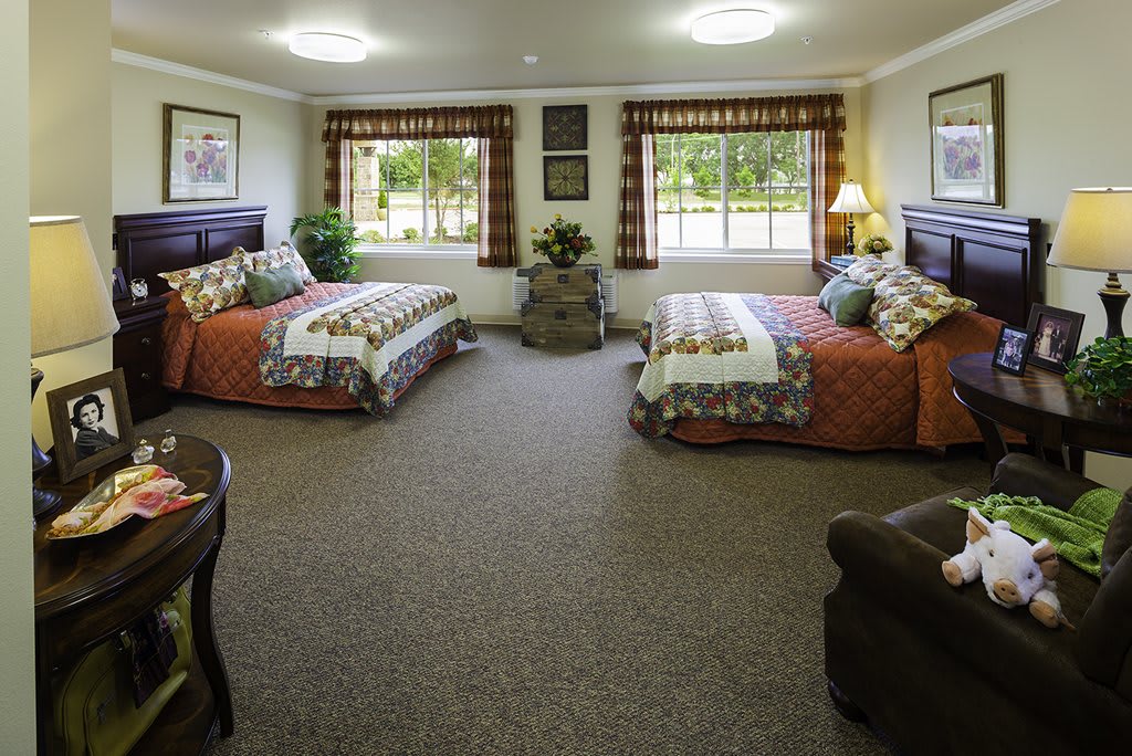 A cozy bedroom with two beds, featuring warm decor and large windows.